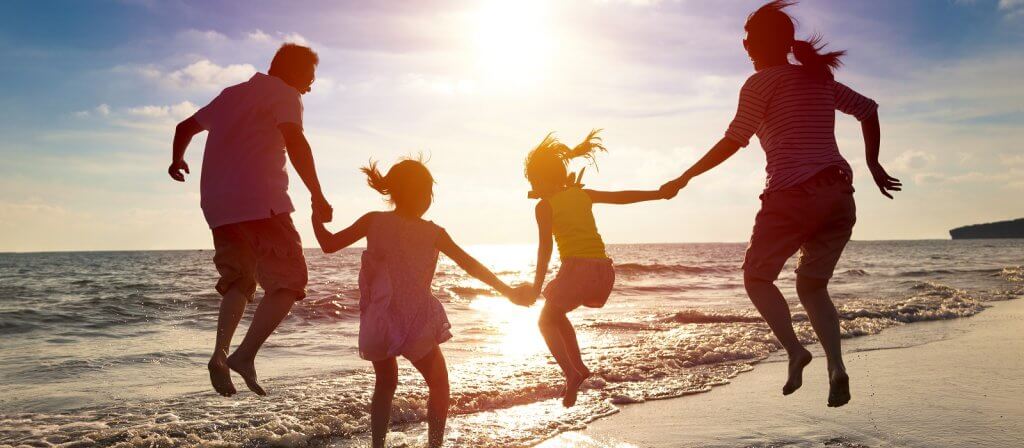 Famiglia che salta sulla spiaggia al tramonto.