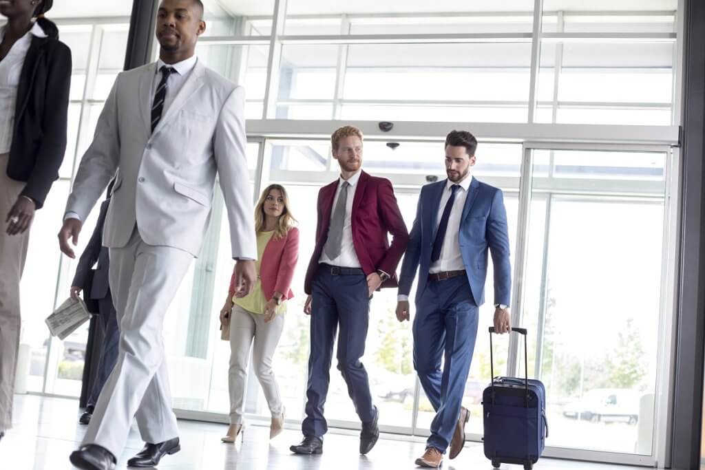 Un gruppo di persone in abbigliamento formale cammina in un ambiente moderno.