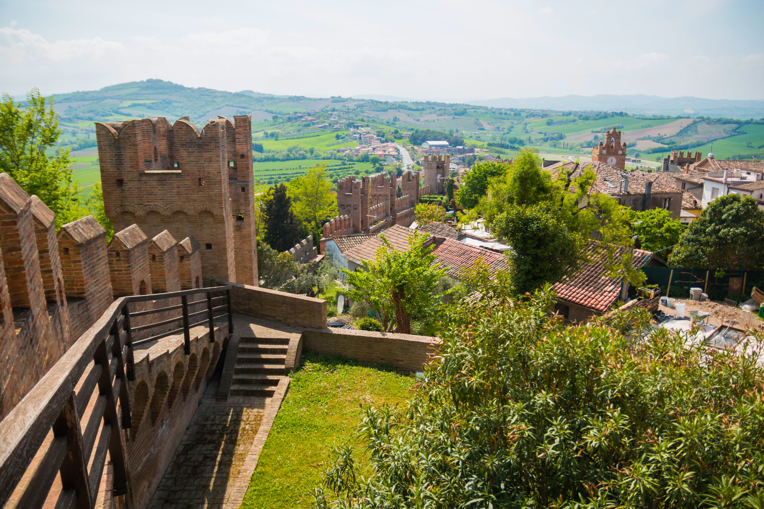 Veduta panoramica di una città medievale con mura antiche e paesaggio collinare.